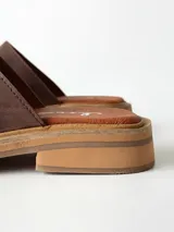 Sandalias de cuero color chocolate, con faja ancha en el empeine, plantilla de gamuza y suela plana con taco bajo.