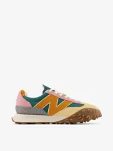 Zapatillas New Balance modelo UXC72 de diseño vanguardista con punta cuadrada. Presentan una combinación de colores vibrantes que incluye verde, amarillo, rosa y gris, confeccionadas en una mezcla de gamuza y malla. Destacan por su suela de goma con relieve pronunciado y el logo N lateral en color amarillo.