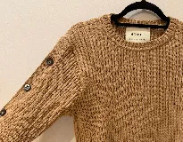 Sweater color camel de tejido de punto acanalado, con cuello redondo y botones decorativos en las mangas. Hecho en Uruguay.