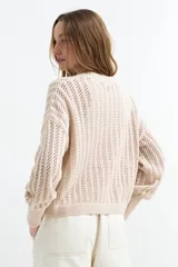 Cardigan beige de tejido calado con escote en V, manga larga y cierre frontal con tres botones.