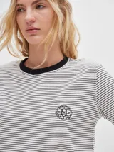 Remera de manga larga con cuello redondo y estampado a rayas horizontales en tonos marrón y negro. Tiene un logo bordado en el pecho de color rojo.