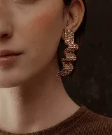 Par de aros colgantes con forma geométrica irregular, recubiertos de strass negros sobre base plateada.