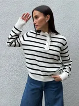 Sweater de punto a rayas horizontales blancas y negras, con cuello redondo, cierre frontal con botones y detalles de puntilla en el cuello y los puños.
