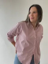 Camisa celeste de corte holgado, con cuello clásico, cierre frontal con botones, bolsillo en el pecho y mangas largas con puños abotonados.