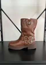 Bota tipo biker de caña media en cuero vegano color marrón, con suela track y múltiples correas con hebillas metálicas plateadas en el tobillo y la parte superior de la caña.
