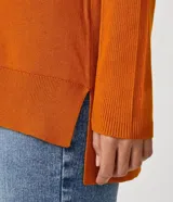 Blusa de punto color naranja, de viscosa de manga larga, cuello alto y detalles acanalados en la manga.