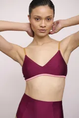 Top de bikini triángulo de color bordó con tirantes finos mostaza y detalle de tira inferior en color rosado.