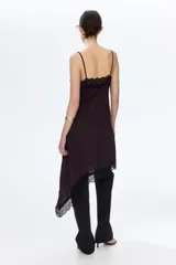Vestido midi de punto interlock con ribete de encaje negro en el escote y bajo asimétrico. Tiene breteles spaghetti y escote en V.