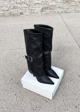 Botas de caña alta color gris, con diseño de solapa plegada y hebilla metálica plateada en el lateral. Presentan punta fina y taco kitten bajo.