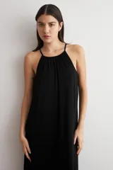 Vestido largo negro de lurex, con escote halter y diseño fluido y acampanado.