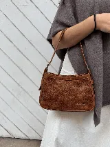 Cartera de cuero vacuno color marrón con efecto avejentado, diseño compacto, cierre superior y correa ajustable para llevar al hombro. Cuenta con la inscripción "Sagali" grabada en el frente inferior.