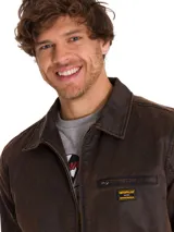 Chaqueta de estilo chore en tejido de sarga encerada color marrón, con cierre frontal metálico, cuello camisero y bolsillo con cierre en el pecho. Presenta un diseño de corte clásico con forro interno estampado.
