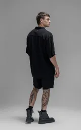 Camisa de manga corta con cuello solapa, confeccionada en lino. Presenta un corte oversize y cierre frontal con botones.