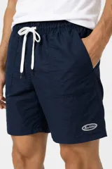Short negro de poliéster de corte recto, con cintura elástica con cordón de ajuste blanco, bolsillos laterales y pequeño logo bordado en el lateral izquierdo.
