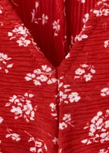 Vestido midi rojo con estampado floral blanco, cuello en V, manga corta y detalle de nudo frontal en el pecho.