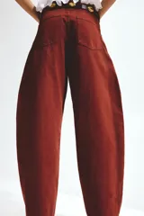 Jeans de corte baggy y tiro alto confeccionados en denim de algodón rígido, con diseño de cinco bolsillos, piernas amplias y cierre frontal con botón y cremallera.