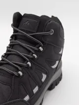 Bota de trekking color negro, con diseño de caña media, confeccionada en materiales sintéticos resistentes y malla transpirable. Cuenta con suela de goma dentada para mayor tracción y cordones reforzados.