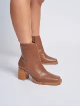Bota de cuero color marrón con caña baja, punta cuadrada y taco geométrico de madera.