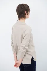 Cardigan de punto color beige, con cuello camisero, cierre frontal de botones y bolsillo aplicado en el pecho. Presenta mangas largas con puños acanalados y un corte recto y holgado.