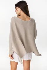 Poncho oversize de tejido de punto con hilos de lurex, color negro, con escote redondo y aberturas laterales en las mangas.