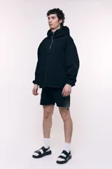 Canguro oversize confeccionado en denim negro 100% algodón, con capucha, cuello alto con cierre metálico frontal, bolsillo frontal tipo canguro y puños con elástico.