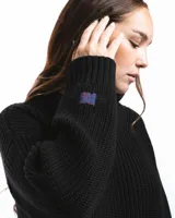 Sweater negro de punto con cuello redondo y corte holgado. Diseño con motivo de zurcido en la manga izquierda.