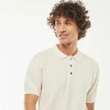 Remera polo de manga corta color crema, de punto con textura en zigzag y cuello clásico con tres botones.
