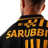 Camiseta de fútbol Puma del Club Atlético Peñarol, edición aniversario manga larga. Diseño con mitad derecha a rayas verticales amarillas y negras, y mitad izquierda negra con escudo retro "CUR" en dorado. Cuenta con cuello tipo polo negro con detalles amarillos y sponsors impresos en el frente y mangas.