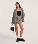 Short pollera de corte sastrero, color gris con estampado de cuadros. Presenta cintura fija, cierre con cremallera, bolsillos y cinturón de poliuretano.