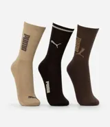 Kit de tres pares de medias deportivas Puma de caña larga. Un par es beige con dos rayas marrones y logo de Puma. Otro par es blanco liso. El tercer par es marrón oscuro con dos rayas blancas y logo de Puma. Todas están confeccionadas en algodón.