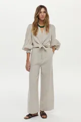 Pantalón de lino color beige, de corte ancho y relajado, con cintura alta y bolsillos laterales.