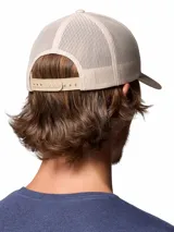 Gorro tipo trucker Columbia Mesh Snap Back de color beige, con visera curva en tono tostado, paneles traseros de malla transpirable y un parche frontal bordado con diseño de montañas y el logotipo de la marca.