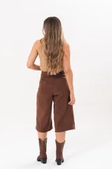 Bermuda de silueta amplia y tiro medio, color marrón chocolate, con bolsillos delanteros y traseros, cierre frontal con cremallera y botón.