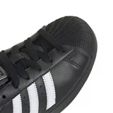 Championes adidas modelo Superstar, de diseño clásico con exterior de cuero negro, las icónicas tres tiras laterales en blanco y puntera de goma reforzada.
