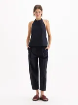 Top Lucille de silueta evasé, calce holgado y corte cropped, confeccionado en poplín Milano de algodón Pima. Cuenta con escote halter de sisa profunda, bretel regulable con ojalillos de níquel que envuelve el cuello, pinzas de entalle y espalda abierta.