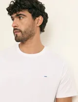 Remera básica de algodón color beige, de manga corta, con cuello redondo y un pequeño detalle bordado en el pecho.