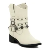 Bota de media caña color blanco con taco bajo y punta fina. Presenta tres tiras horizontales con hebillas y apliques metálicos.