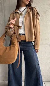 Campera tipo bomber de gamuza con diseño relajado, cierre frontal, cuello camisero y detalles de apliques en los hombros.