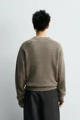 Jersey de punto con textura, corte relajado, cuello redondo y manga larga con terminaciones en rib.