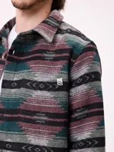 Camisa de manga larga con diseño de estampado étnico en tonos azules y beige. Presenta cuello clásico, cierre frontal con botones y bolsillos en el pecho.