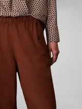 Pantalón cargo de corte relajado, confeccionado en una mezcla de lino y algodón. Presenta cintura elástica, bolsillos laterales y un diseño utilitario con un acabado en color marrón.