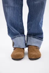 Zueco de cuero vacuno en color marrón oscuro, con diseño de punta cerrada, ajuste mediante hebilla metálica lateral y suela de corcho con base de goma.