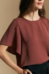 Top de color azul, con escote redondo a la base y mangas cortas amplias con caída fluida. Presenta una silueta relajada y un diseño minimalista.