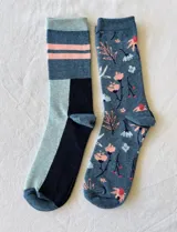 Pack de dos pares de medias de algodón. Un par con diseño geométrico en tonos azul, celeste y rosa. El otro par con estampado floral en tonos rosa y celeste sobre fondo azul.