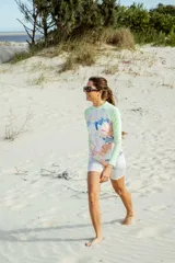 Conjunto deportivo de natación compuesto por una remera de manga larga con protección UV y una calza tipo biker. La remera presenta mangas color verde menta y un panel frontal con estampado floral en tonos pasteles. La calza a juego mantiene el mismo estampado floral.