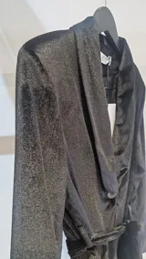 Blazer negro de terciopelo con hombreras, solapas cruzadas, bolsillos con solapa y lazo ajustable en la cintura.