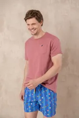 Short de baño azul vibrante con estampado repetitivo de cruces pequeñas en blanco y rojo. Presenta cintura elástica fruncida y cordón de ajuste trenzado en color coral con puntas de neón verde lima.