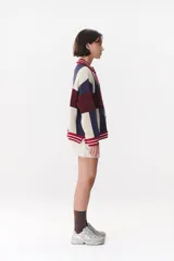 Cardigan de punto con diseño de bloques de color en tonos marrón, beige y verde. Presenta cuello redondo, cierre frontal con botones, mangas largas con hombros caídos y logo bordado en el frente. Posee terminaciones en rib a rayas.