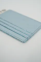 Tarjetero minimalista de color dorado metálico, con múltiples ranuras para tarjetas.