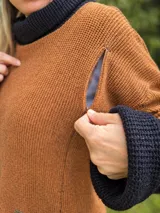 Polerón de punto inglés color marrón topo, con cuello alto tipo polera, mangas largas y cierres laterales decorativos.